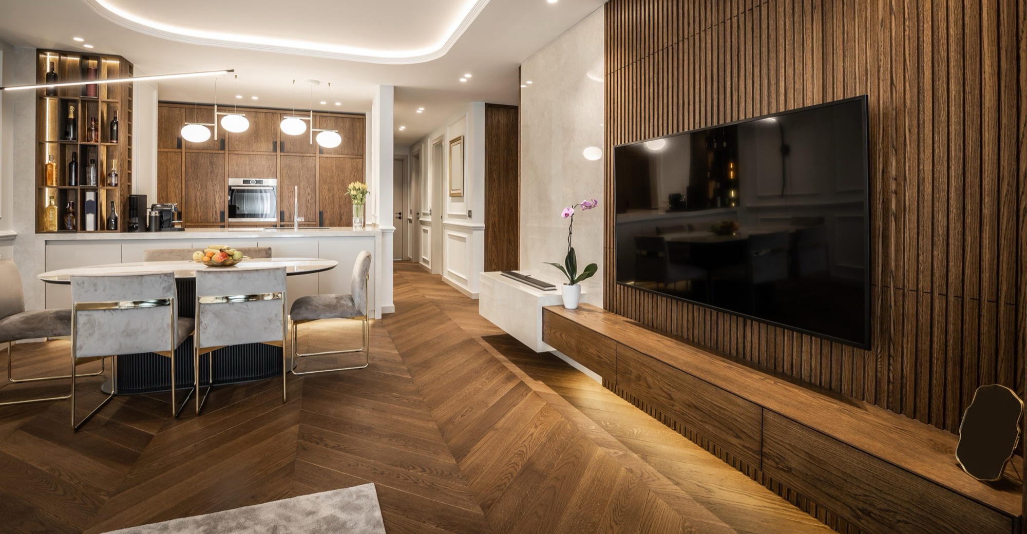 Sala integrada com painel ripado de madeira, piso em espinha de peixe e cozinha planejada